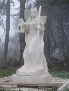 Raphaëlle Duval sculptant La Gardienne, sculpture monumentale en pierre calcaire de Thénac, 2,50 m de hauteur, située au lieu-dit Caillaud, Boscamnant (17360), œuvre contemporaine extérieure.
