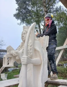 Raphaëlle Duval en train de sculpter La Gardienne, sculpture monumentale en pierre calcaire à Boscamnant (17360), œuvre d’art contemporaine visible en extérieur