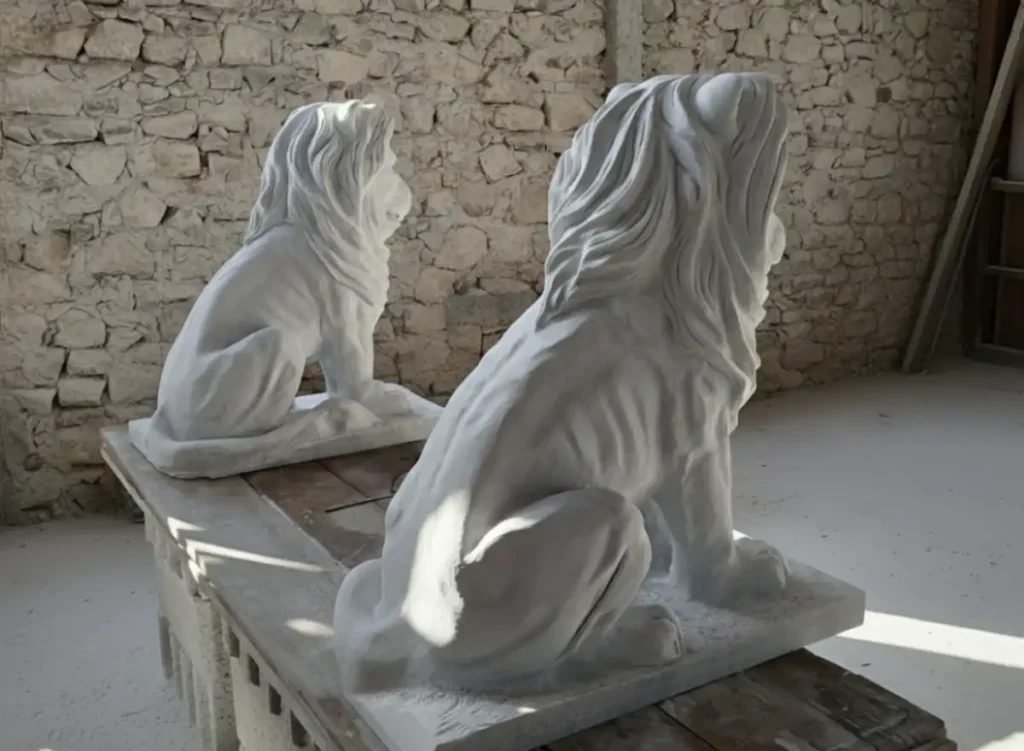 Deux sculptures en marbre de Carrare représentant des lions vues de dos, réalisées par l’artiste Raphaëlle Duval, dimensions 80 × 70 × 40 cm.