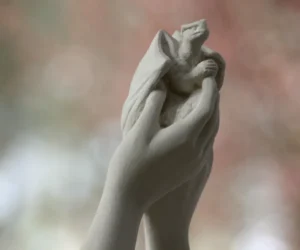 Sculpture d’un bébé dragon tenu dans les mains d’une femme, création de Raphaelle Duval à Bassens 33530