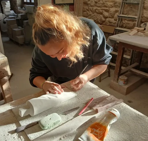 Élève des Ateliers Raphaëlle sculptant un tube de dentifrice en pierre dans l'atelier de Bassens (33530)