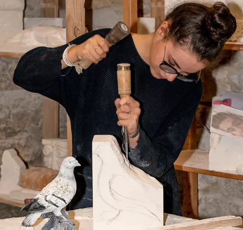 Élève des Ateliers Raphaëlle sculptant un oiseau en pierre au maillet et au ciseau à partir d'une figurine de référence, Bassens (33530)