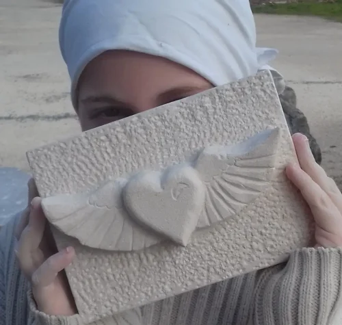 Élève des Ateliers Raphaëlle présentant un bas-relief en pierre représentant un cœur ailé, Bassens (33530)